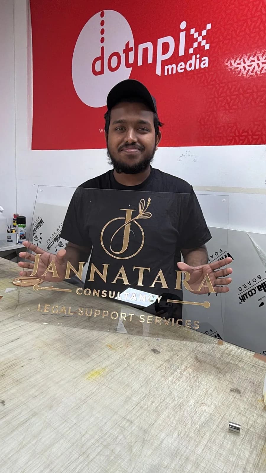 A finished clear acrylic sign with gold lettering, held up in the studio