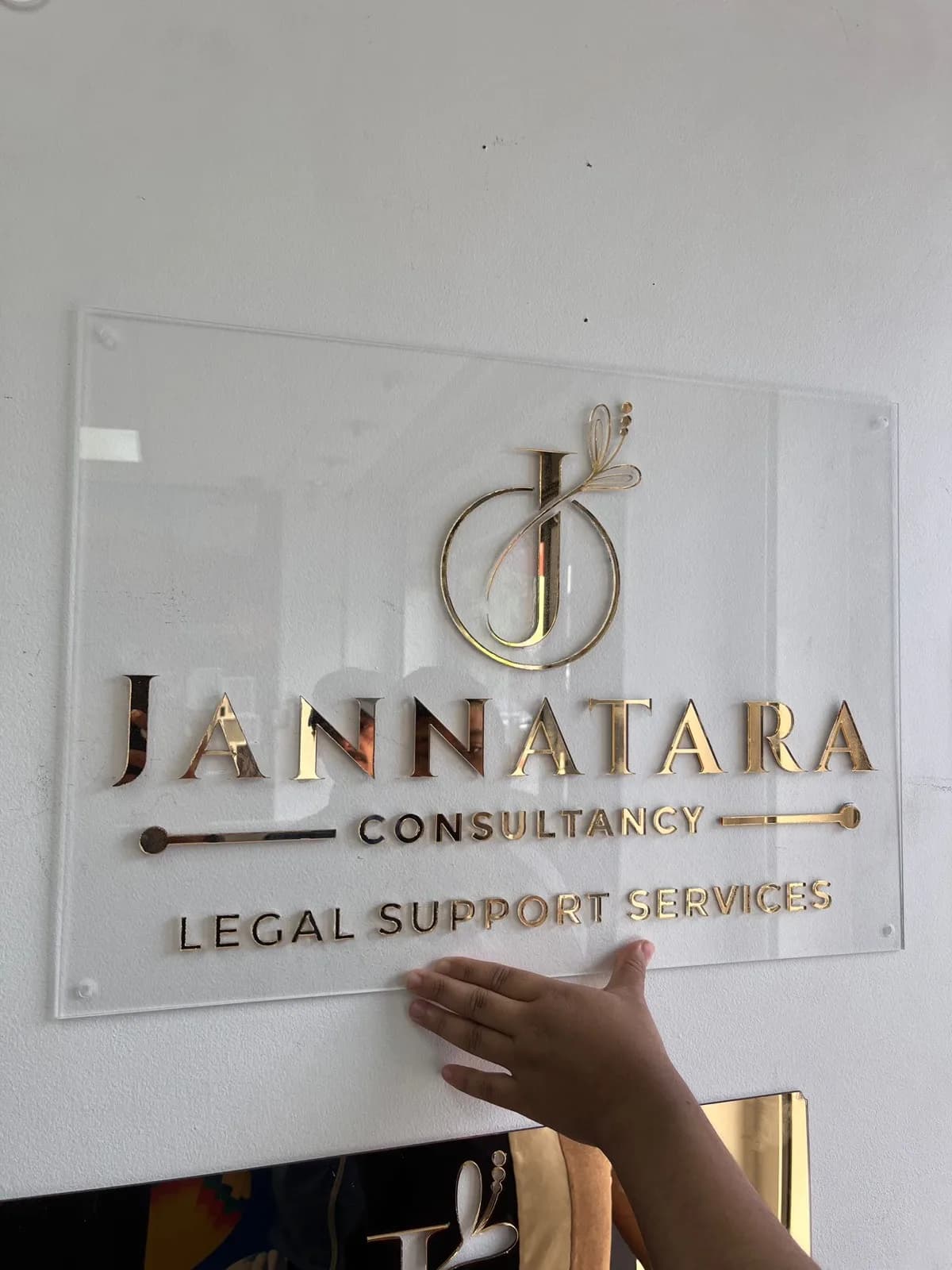 The same gold-on-clear acrylic sign, mounted on the client's wall